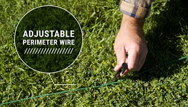 A user placing the perimeter wire out in their lawn with the provided hooks